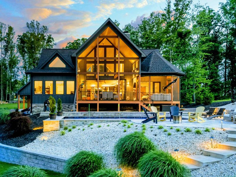 Twilight Full View - The complete estate at dusk, with the A-frame home, pool, fire pit, ornamental landscaping, and dock all beautifully illuminated.