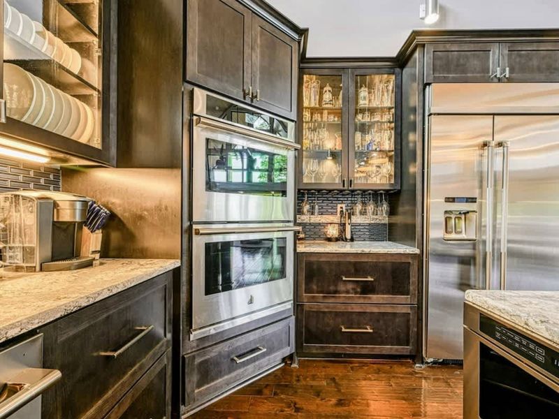 Kitchen Appliances - A Keurig station, built-in double ovens, glass-front glassware cabinet, and professional refrigerator line the kitchen's back wall.