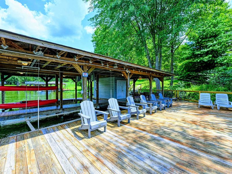 Dock - Covered dock with Adirondack chairs facing the open water and red kayak stored overhead.