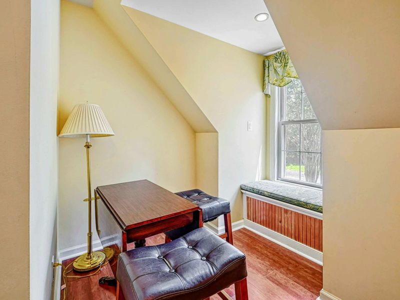 Reading Nook - Desk with leather ottomans, floor lamp, and dormer window seat on the upper level.