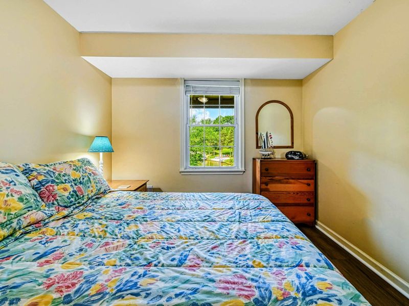 Bedroom 6 - Queen bed with floral quilt, cedar armoire with mirror, and cozy dormer window nook on the upper level.