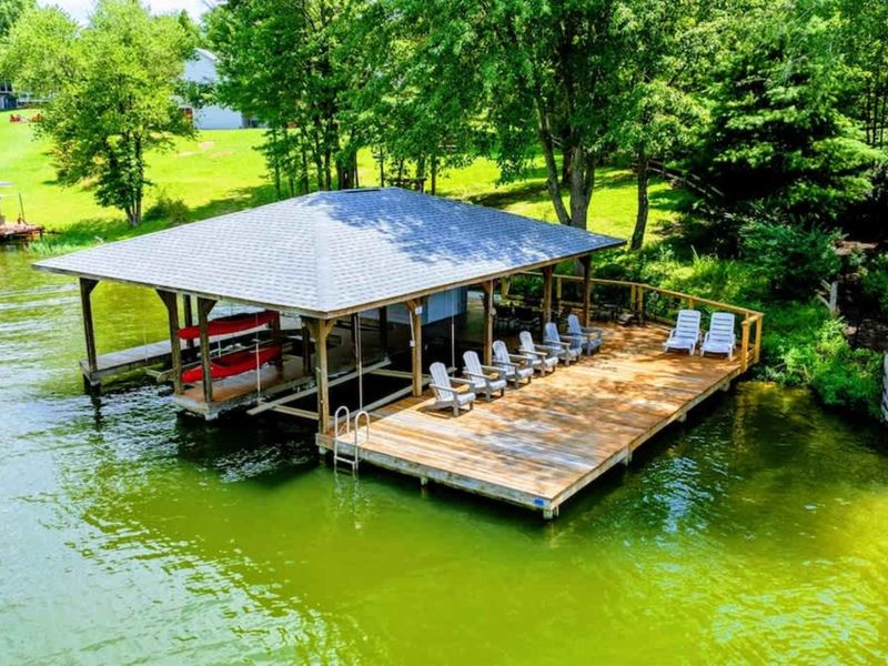 Dock - Aerial view of the covered dock with Adirondack chairs, boat slips, and kayak storage on the water.