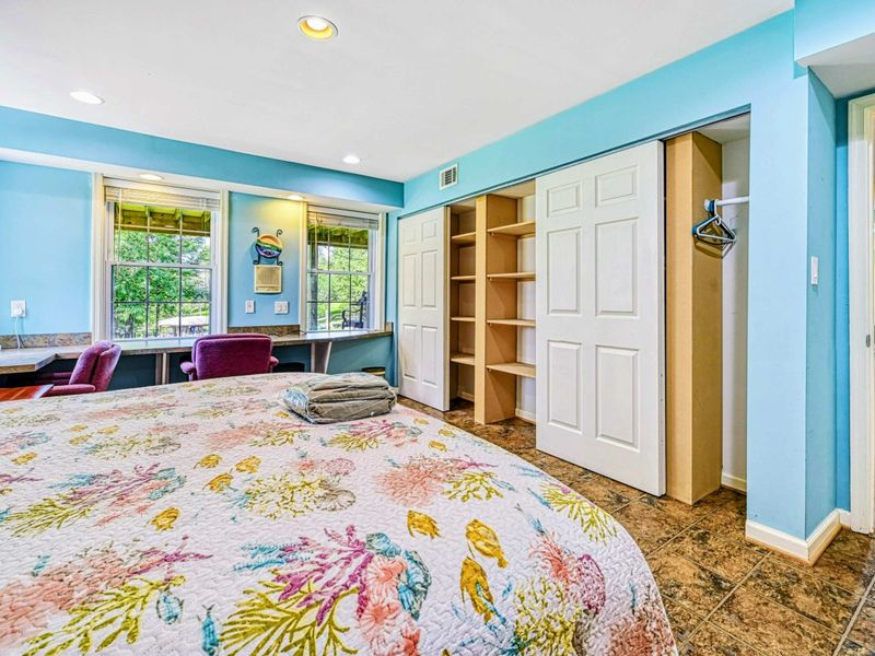 Bedroom 5 - Alternate view showing the desk area, built-in closet with open shelving, and coral quilt.
