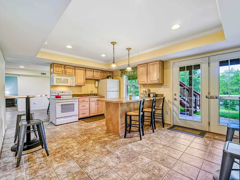 Lower Level Kitchenette - Maple cabinets with beadboard island, bar stools, pendant lights, and French door to the yard.