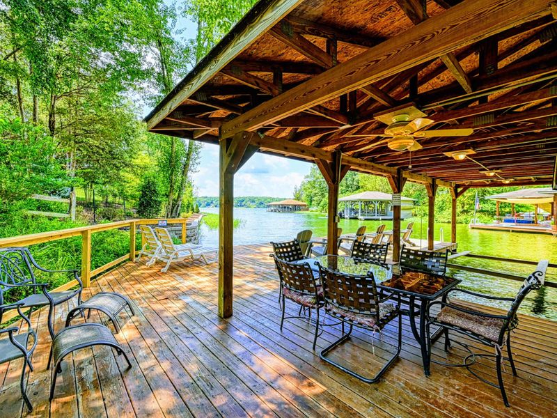 Dock - Covered seating area with metal dining set, ceiling fans, and open lake views from the shaded deck.