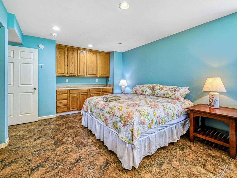 Bedroom 5 - Oak built-in cabinets, king bed with bedside lamps, and en suite bathroom entry on the lower level.