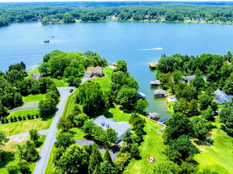 Aerial - High view of the lake cove with waterfront homes, docks, and the peninsula beyond.