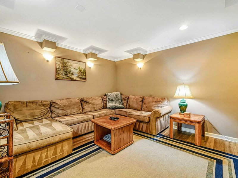 Lower Level Media Room - Plush sectional with decorative wall sconces, landscape art, and striped area rug.