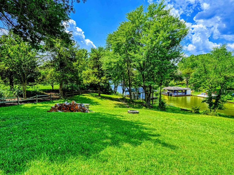 Yard - Expansive green lawn with fire pit, views through the trees to the dock and lake.