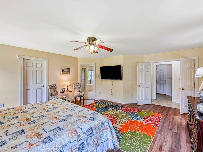 Primary Suite - TV wall with closets, en suite entry, accent chair, and nautical sailboat lamp.