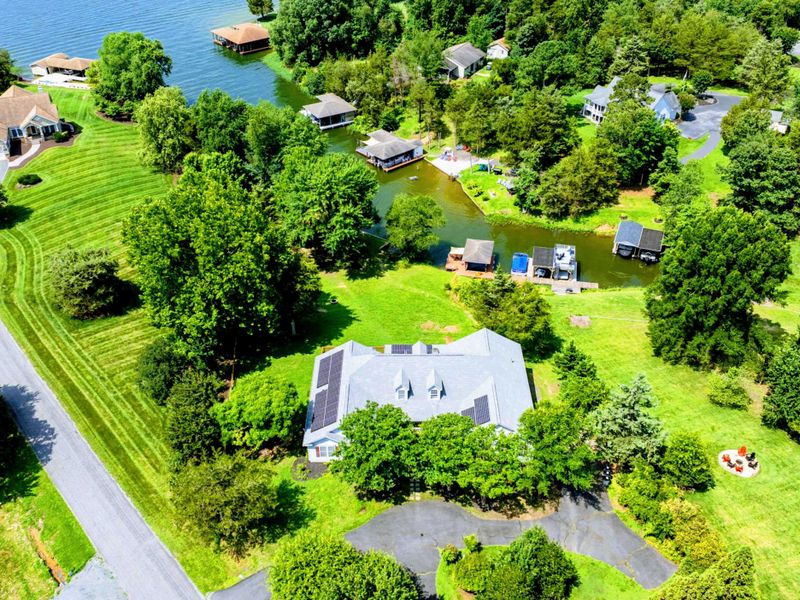 Aerial - Wider view of the home and neighborhood with the lake shoreline in the background.