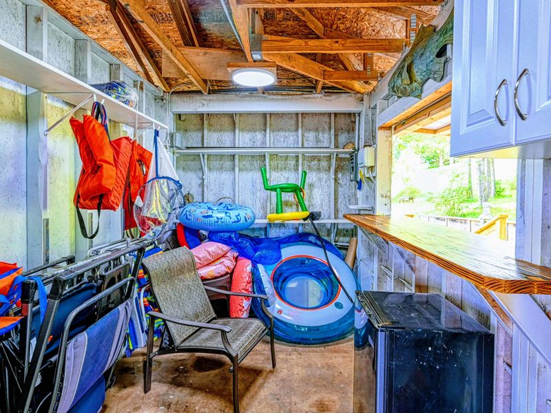 Dock Storage - Interior stocked with life jackets, beach chairs, pool floats, and lake toys for guest use.