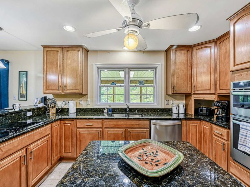Kitchen - Double wall ovens, sink with window view, and granite island in the well-equipped cooking space.