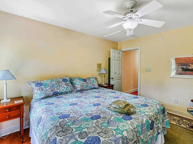 Bedroom 2 - King bed with sea-themed blue bedding, ceiling fan, and harbor painting on the wall.