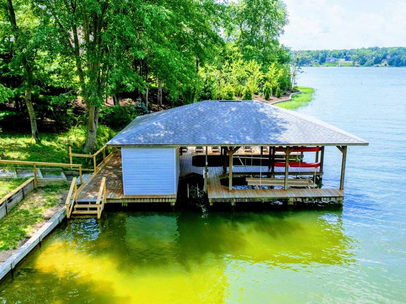 Dock - Covered boathouse from the water with blue siding, roll-up storage door, and life vest window.