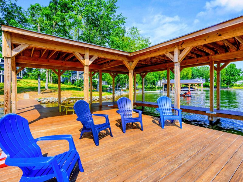 Dock Lounge - Blue and white Adirondacks fill the covered dock, ready for cold drinks, lake breezes, and the kind of afternoon nobody wants to end.