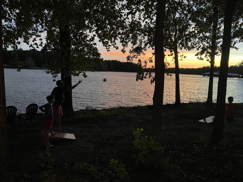 Lakeside Sunset - Cornhole at the water's edge as the sky turns gold over the lake, the kind of evening that becomes the trip's favorite memory.