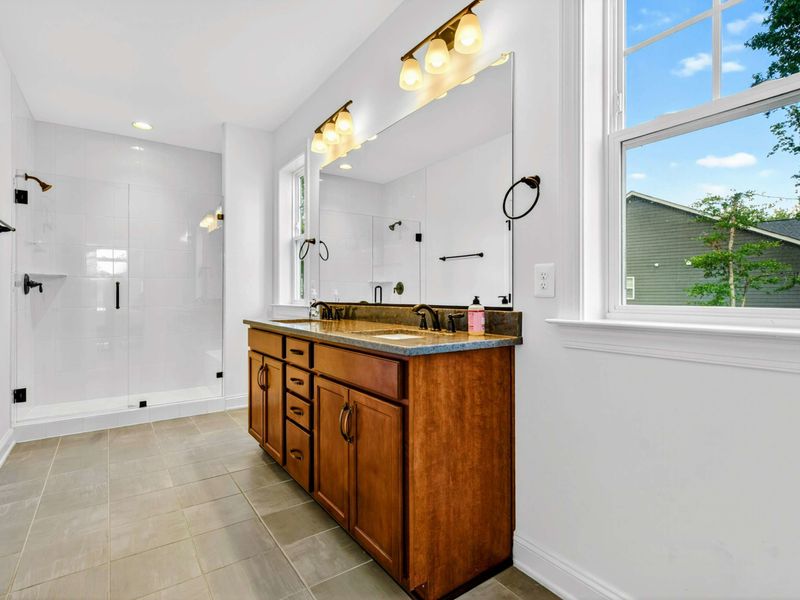 Ensuite Bathroom - Double vanity, glass-enclosed walk-in shower, and warm wood cabinetry make this feel more spa than functional.