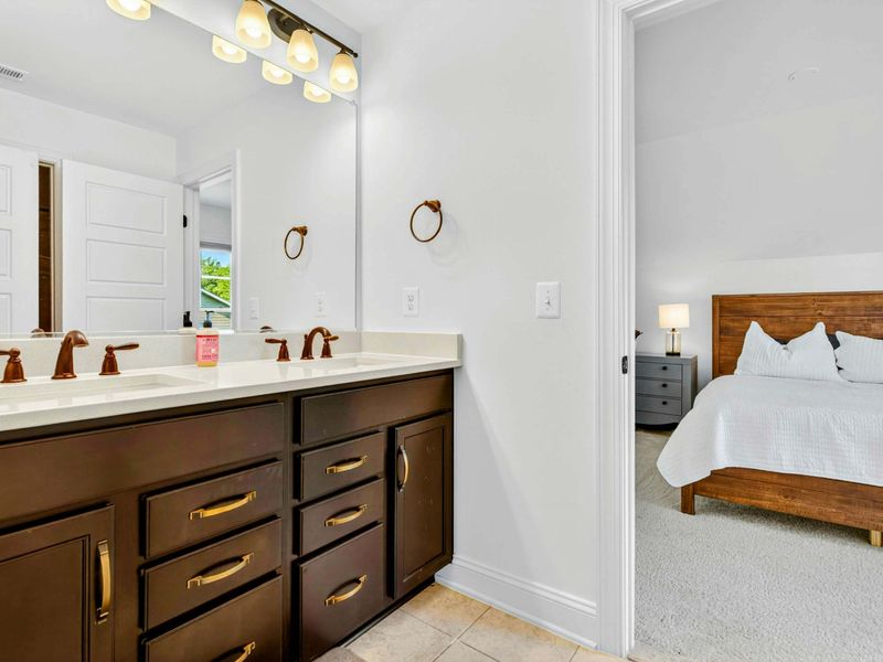 Upper Bathroom - Dark wood double vanity with brass fixtures and a wide mirror, shared by the upstairs bedrooms.