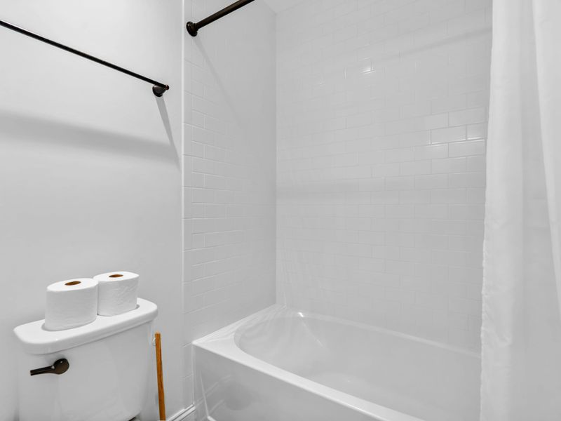 Upper Bathtub - A classic tub-and-shower combination with subway-tile walls and brass fixtures.