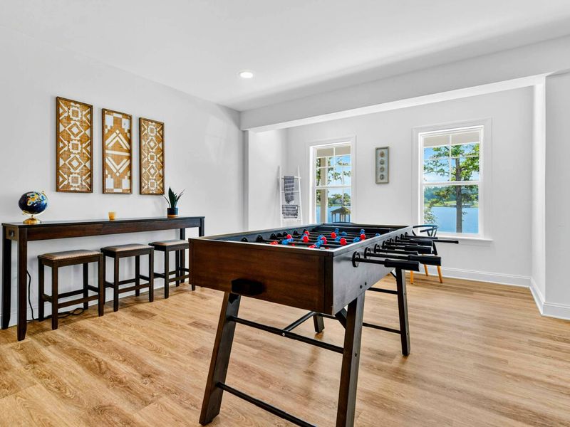 Game Room - A professional foosball table and pub-height seating beside windows that frame the lake through the trees.