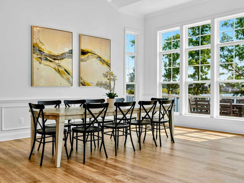 Dining Room - A long farmhouse table seats ten under abstract artwork, with French windows opening to the deck and lake beyond.