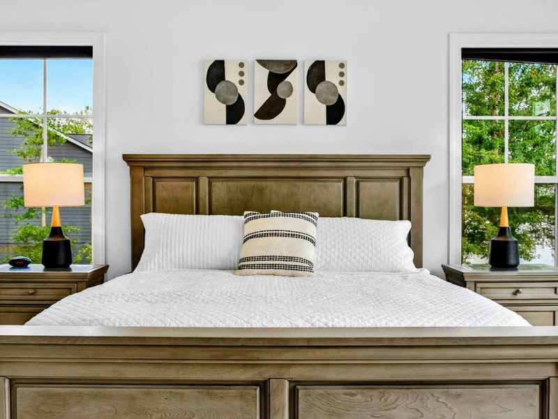 Primary Suite Bed - Crisp white bedding, dual nightstands, and warm wood frame complement modern art accents above the king bed.