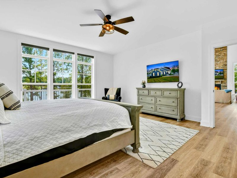 Primary Suite - Smart TV, dresser, and reading chair share the room with lake views and balcony access.