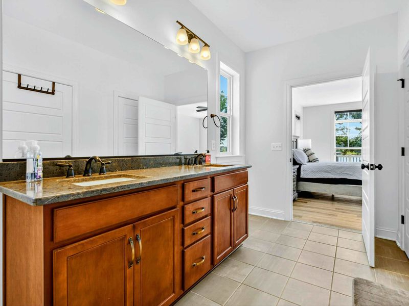 Ensuite Vanity - Cherry wood double vanity with granite counters and a wall-length mirror in the primary bath.