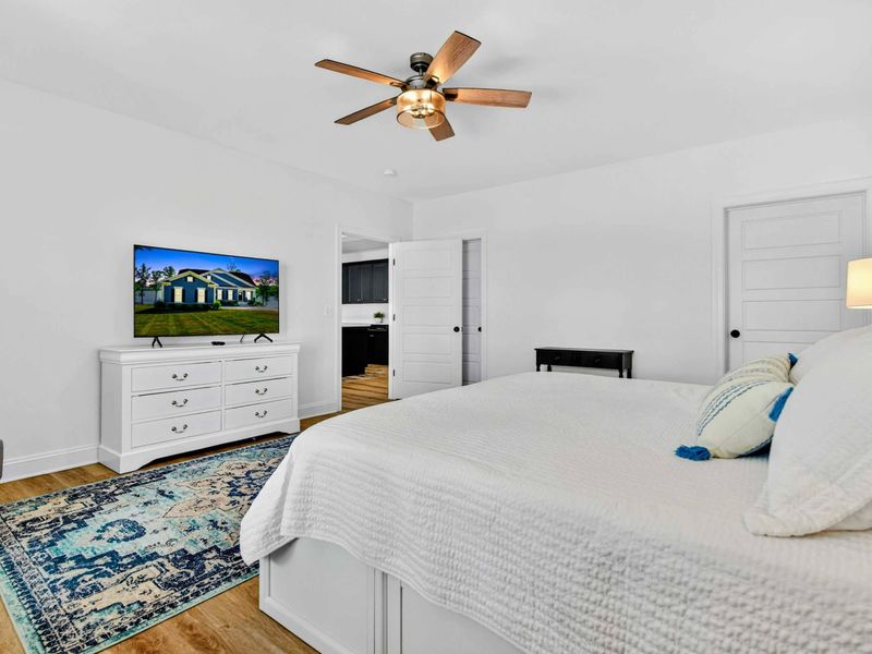 Main Level Bedroom - A wider view shows the king bed, ensuite entry, closet, and dresser, all bathed in natural light.