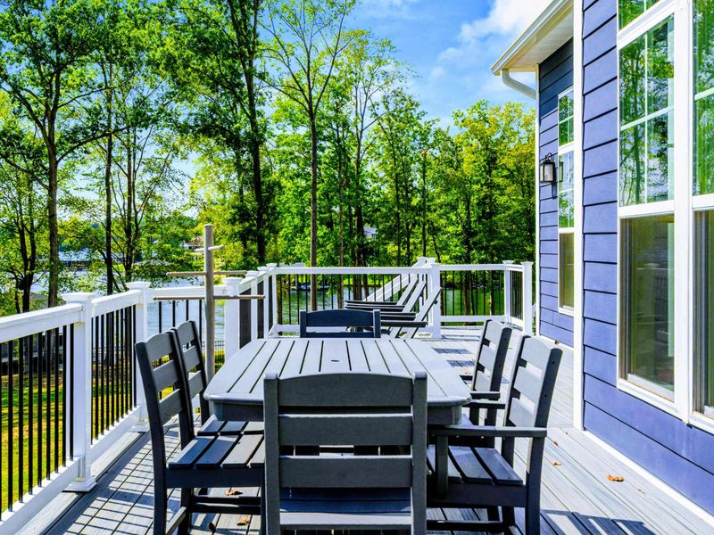 Deck Lounge - The wide Trex deck hosts both dining and seating, with the home's blue siding and white trim framing the lake view.