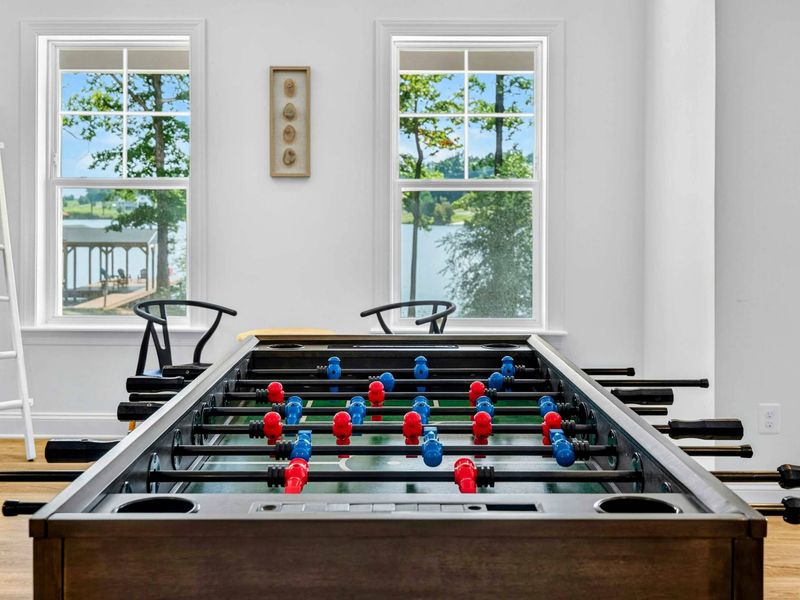 Foosball - Close-up of the foosball table with lake views through the windows, ready for friendly competition.