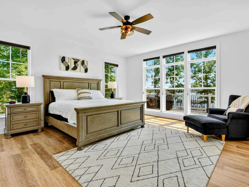 Primary Suite - King bed with lake views, French doors to a private balcony, and an armchair for quiet mornings.