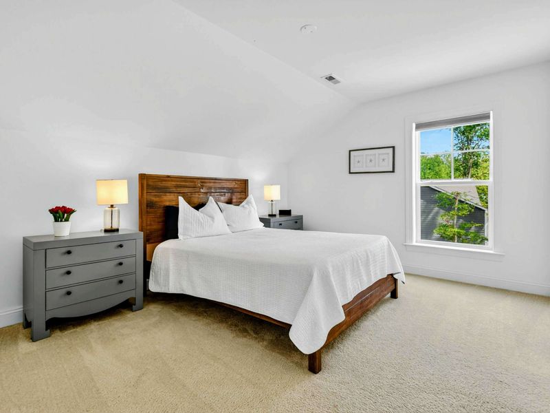 Upper Bedroom - A queen bed with rustic wood headboard, matching nightstands, and oversized windows facing the trees.