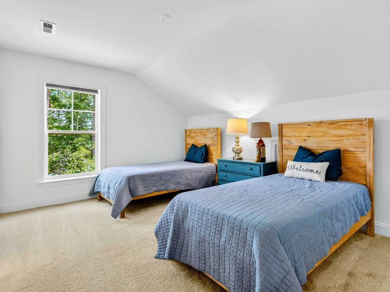Twin Bedroom - Two twin beds with rustic wood headboards, a teal nightstand, and ample carpeted space for kids or extra guests.