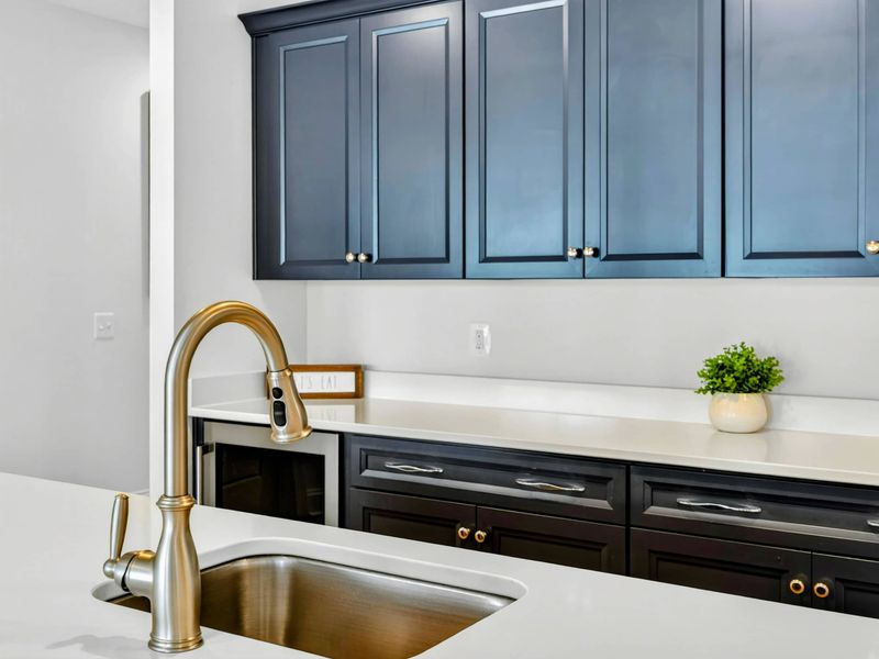 Bar Detail - Gold gooseneck faucet, navy cabinetry, and white quartz counters bring a polished finish to the lower bar.