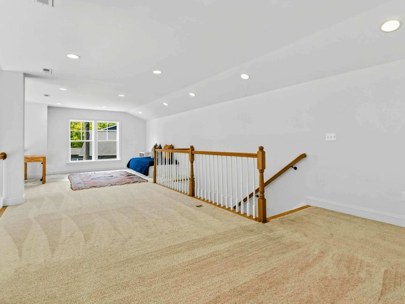Loft Landing - The carpeted loft area with oak railings overlooks the great room and connects the upstairs bedrooms.