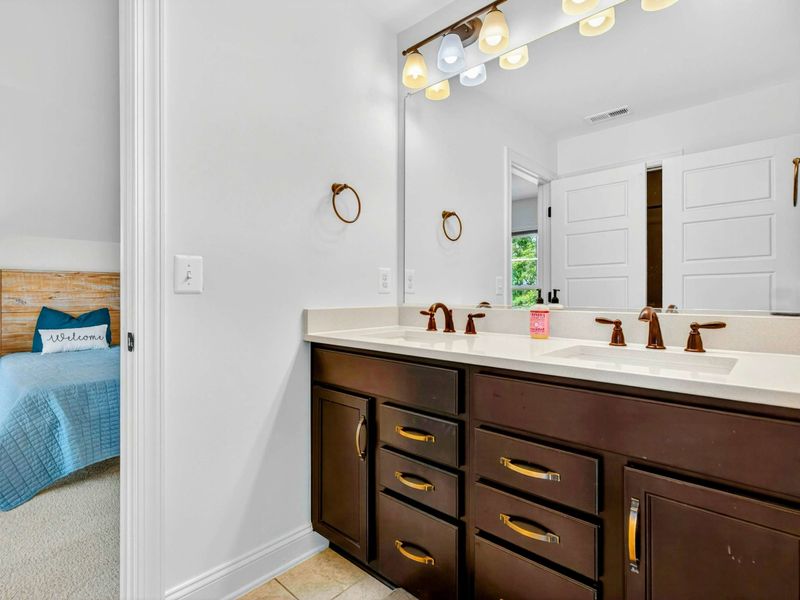Upper Vanity - A second dark wood double vanity with brass hardware and quartz counters serves the upstairs guest rooms.