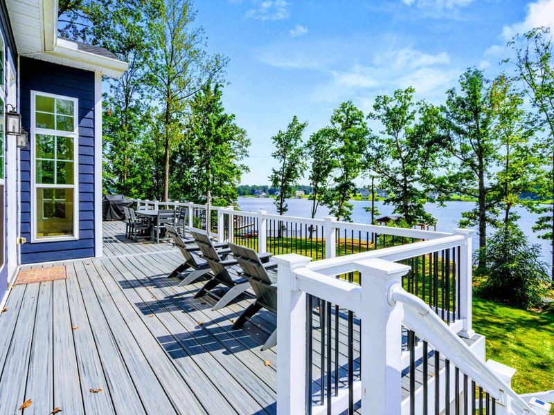 Upper Deck - Loungers and dining sit on the oversized Trex deck, with white railings and panoramic lake views through the trees.