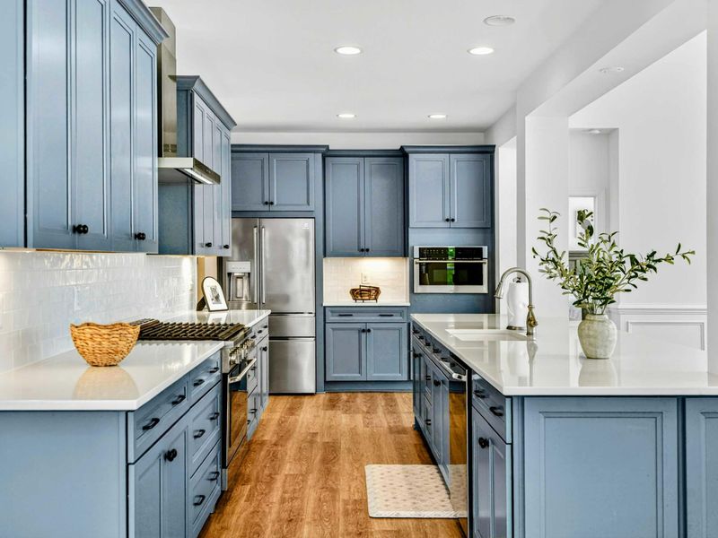 Gourmet Kitchen - Slate-blue cabinetry, white quartz counters, subway-tile backsplash, and stainless steel appliances throughout.