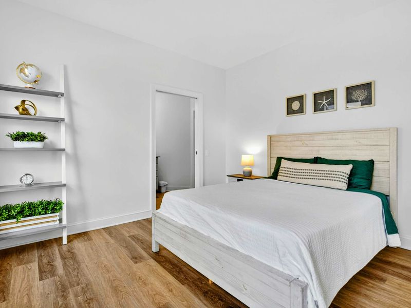 Guest Bedroom - Bright bedroom with coastal-themed art, leaning shelf, and warm wood headboard for restful nights after long lake days.
