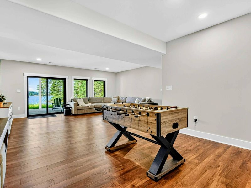 Game Room - Full view with foosball, sectional seating, and lake views through the sliding glass doors.