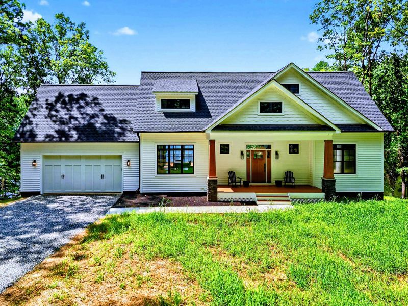 Front Exterior - Craftsman facade with green siding, stone column accents, covered porch, and two-car garage.