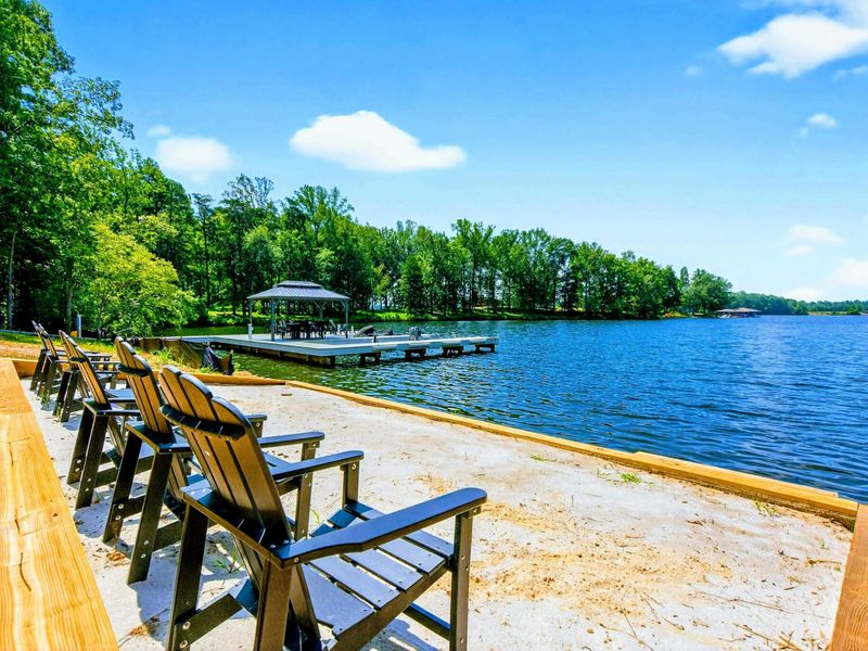 Sandy Beach - Adirondack seating on the sand with the dock and lake sparkling beyond.