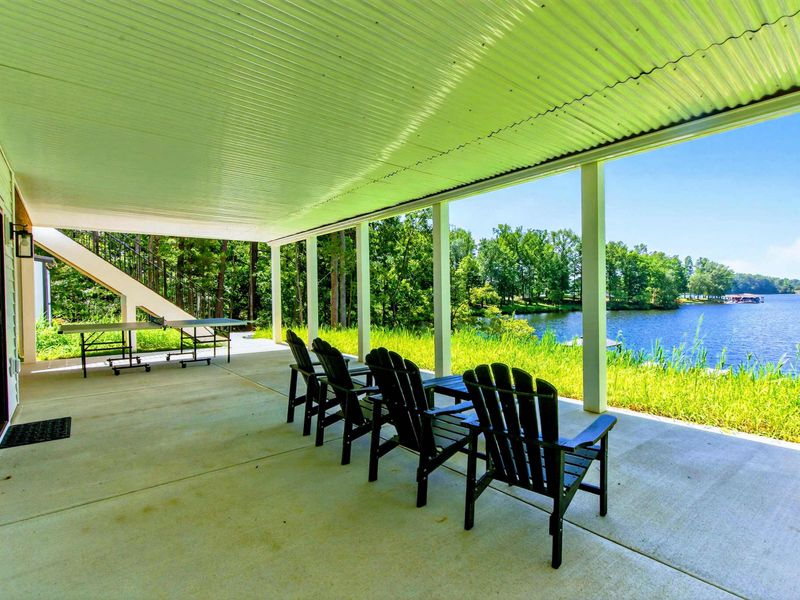 Covered Patio - Full lower patio with ping pong, lounge chairs, and lake views through the columns.