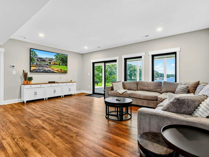 Lower Level Family Room - Plush sectional and large Smart TV with lake view windows and patio access.