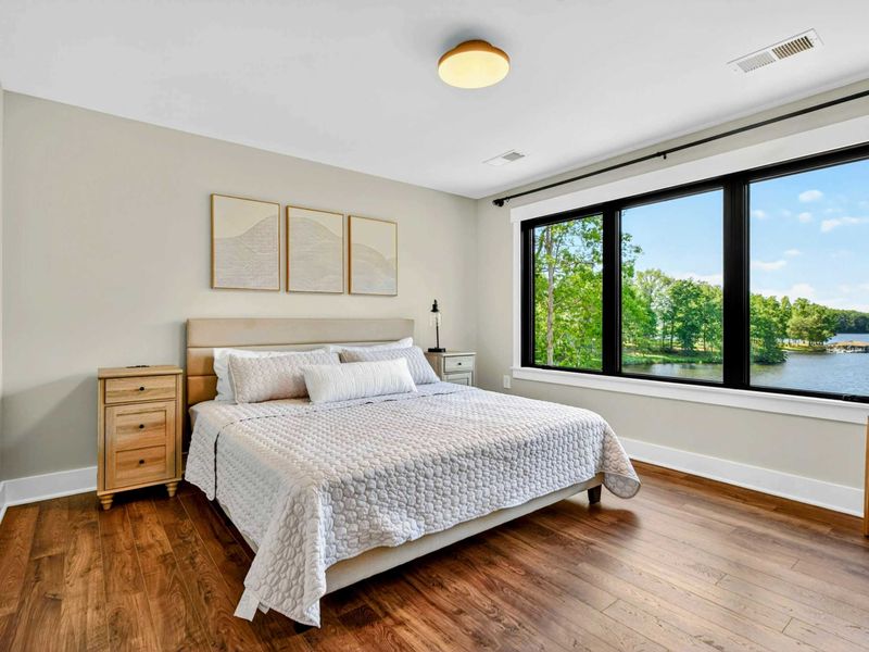 Bedroom 2 - King bed with neutral bedding and abstract art, lake views through large windows.