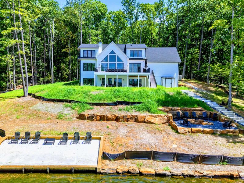 Aerial View - Overhead perspective captures the home, tiered yard, sandy beach, and private dock.