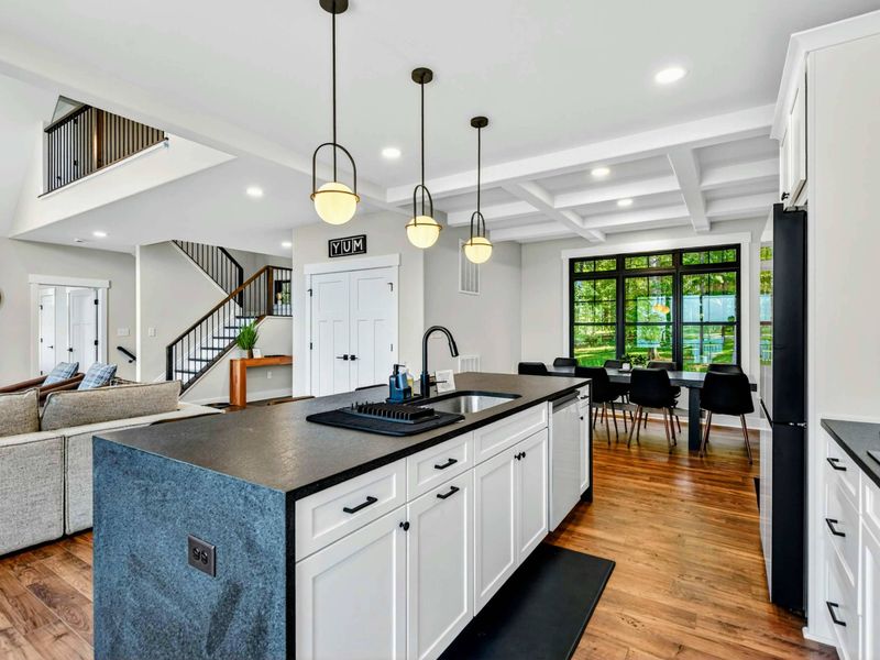 Kitchen - Open layout shows the island, staircase to the loft, and cozy dining nook with coffered ceiling.