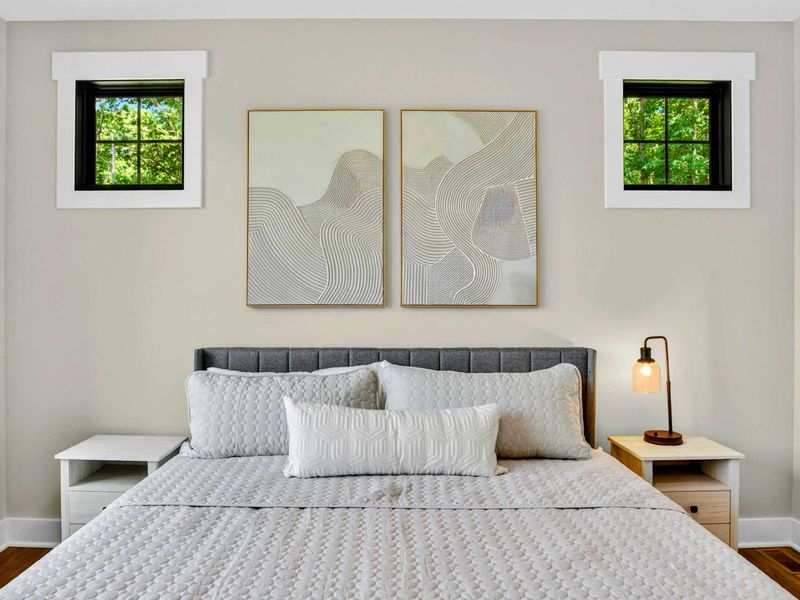 Primary Suite - Close-up of the king bed with wave-inspired triptych art and flanking accent windows.